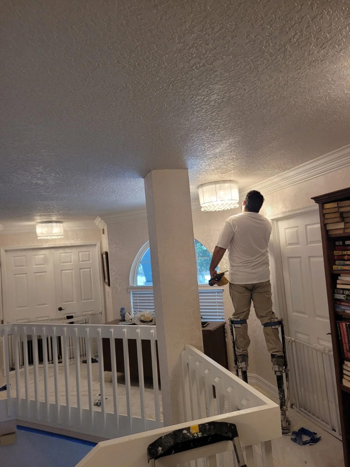Worker on drywall stilts finishing ceiling detail