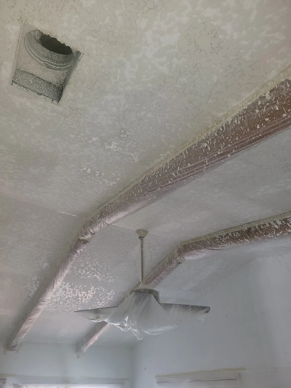 Freshly sprayed ceiling texture with wooden beams carefully masked