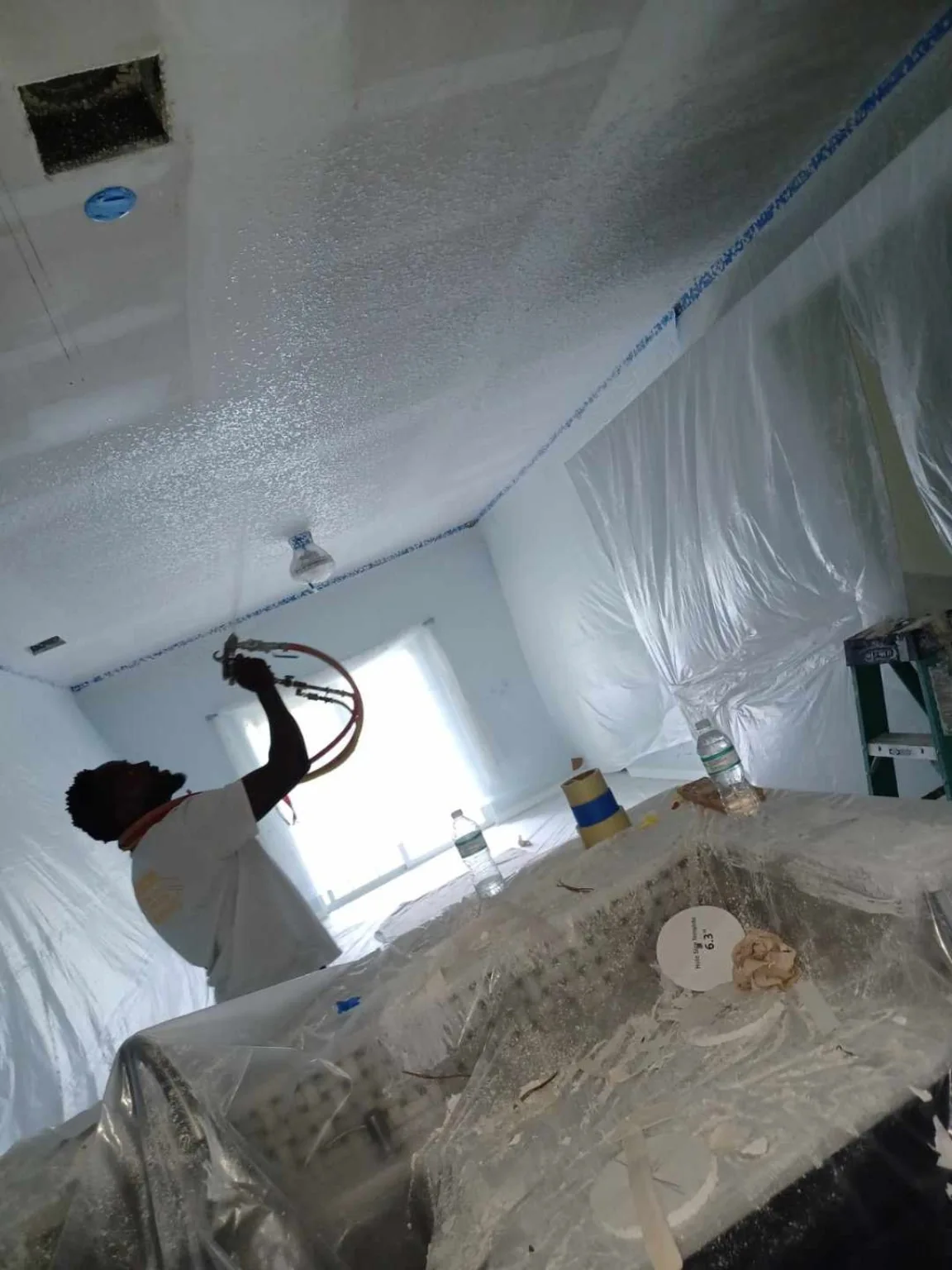Professional spraying ceiling texture with hose
